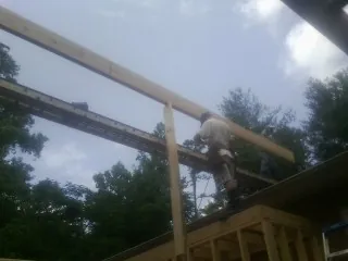 Carpenter setting a ridge beam over a new addition frame — Ice Dam Removal by Roofing Brothers in Nora Springs