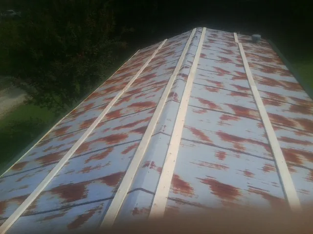 Rusted metal roof panels with new wood purlins before replacement — Storm Damage Roof Repair in Nora Springs by Roofing Brothers