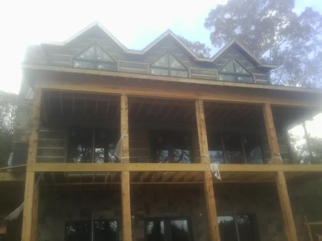 Dormers and porch framing on a large log home under construction — Roof Coating work by our crew in Nora Springs